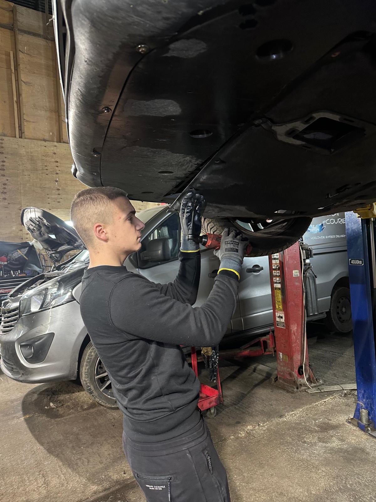 Presleys mechanic working under a van on the ramp